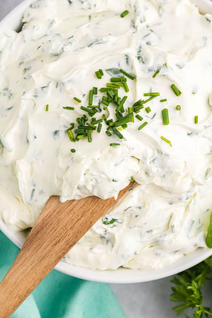knife lifting garlic dip from a bowl.