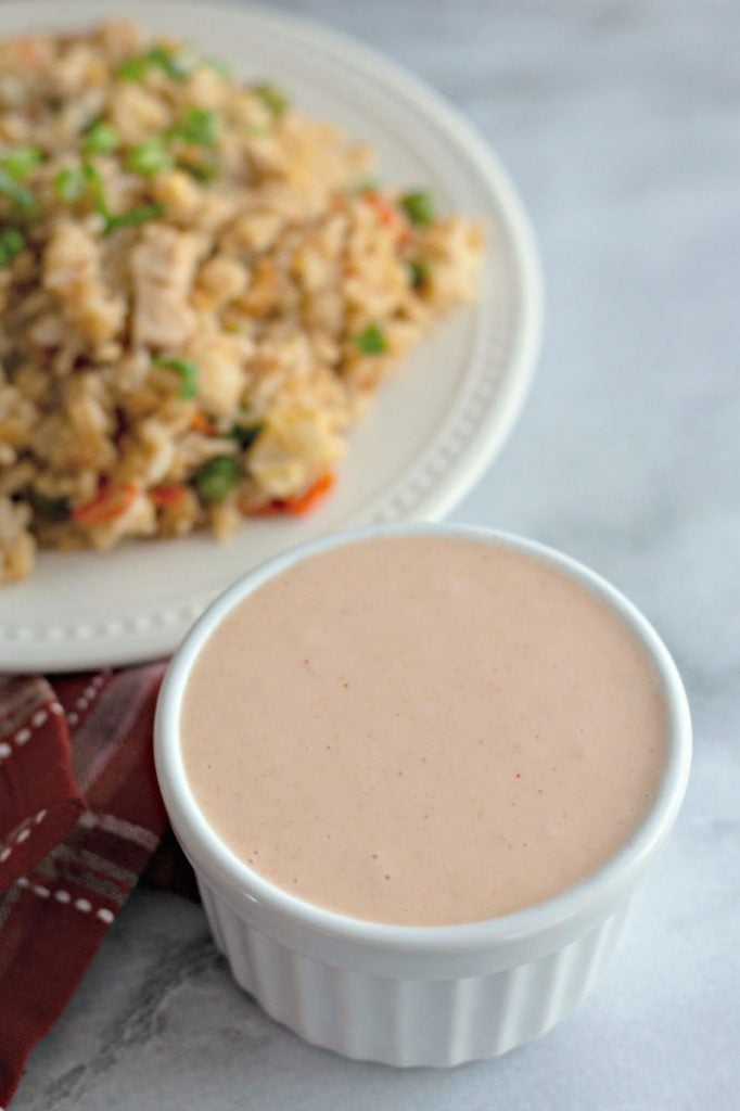white cup of yum yum sauce in front of fried rice