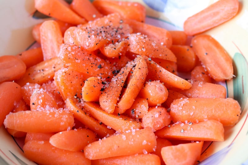 close up of carrots in a bowl with salt & pepper