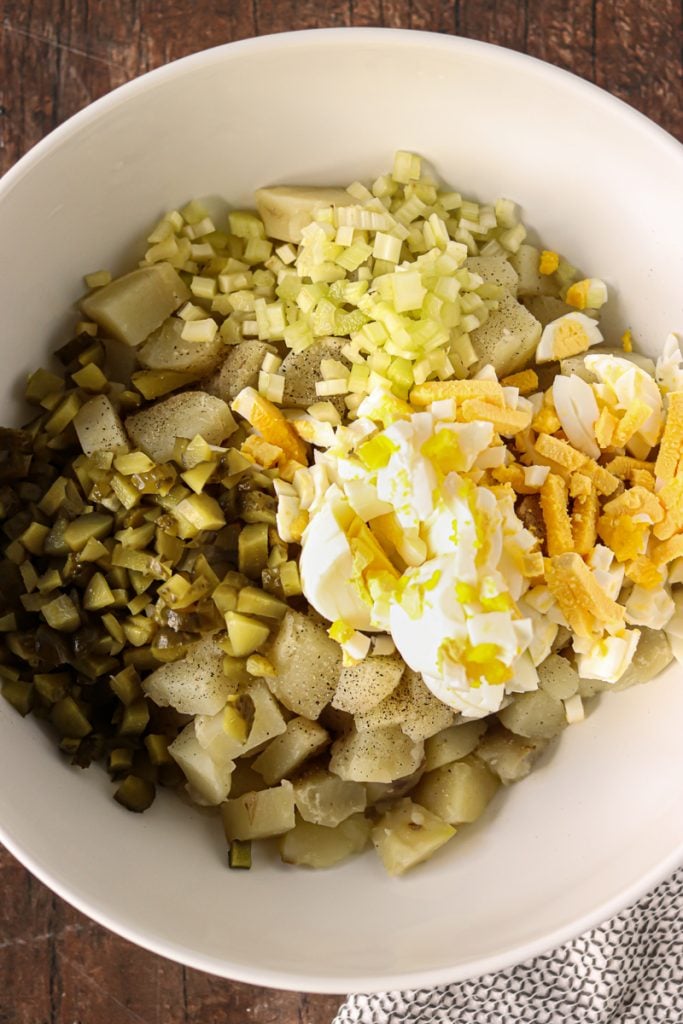 overhead shot of ingredients in a white bowl to make potato salad