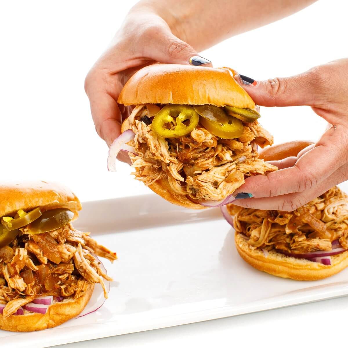 Liz Holding up Sandwich with Slow Cooker BBQ Pulled Chicken