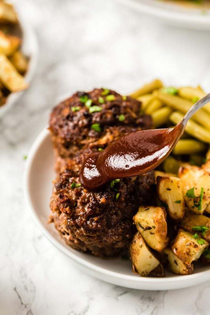 pouring bbq sauce on mini meatloaf