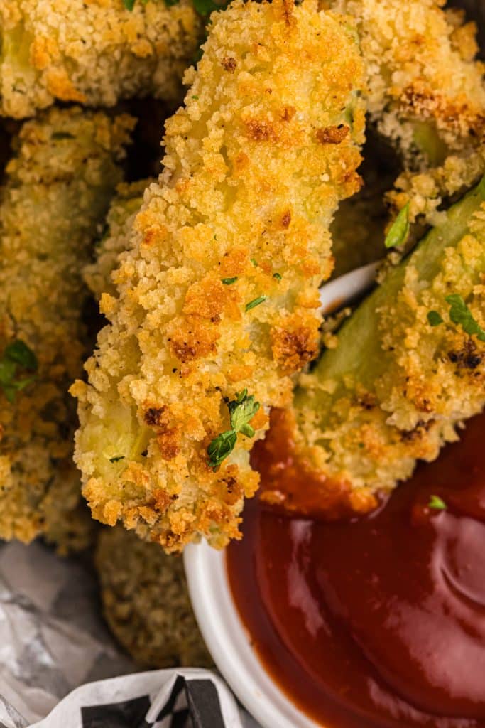 closeup of a crispy panko crusted zucchini fry in sauce.