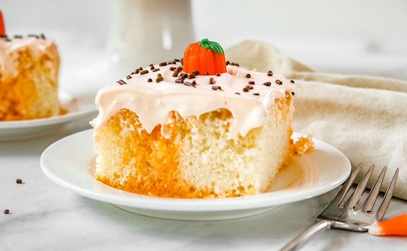 slice of orange poke cake with pumpkin on top