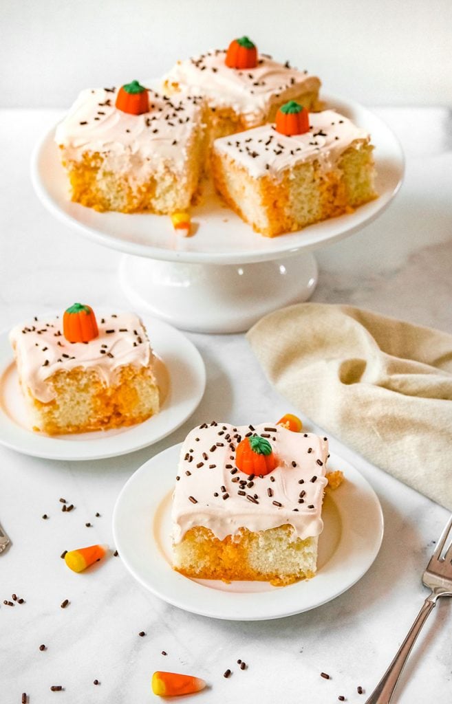 halloween poke cake on a white plate in front of platter of cake slices