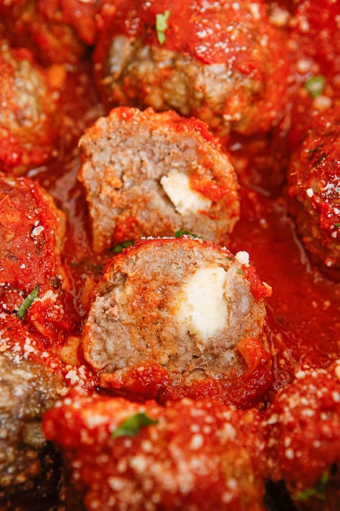 closeup of a mozzarella stuffed meatball in a slow cooker.