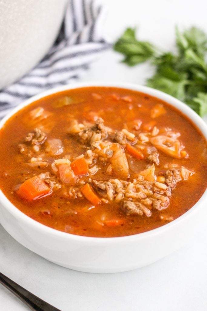 bowl of cabbage roll soup with fresh parsley beside it