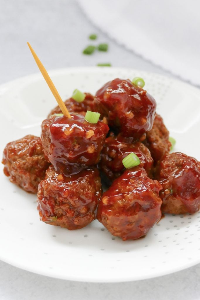 sweet & spicy slow cooker meatballs on a plate with a toothpick on top