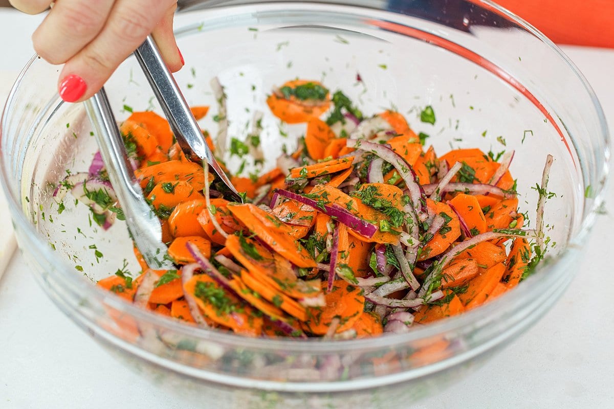 Tossing carrot salad with honey vinaigrette.