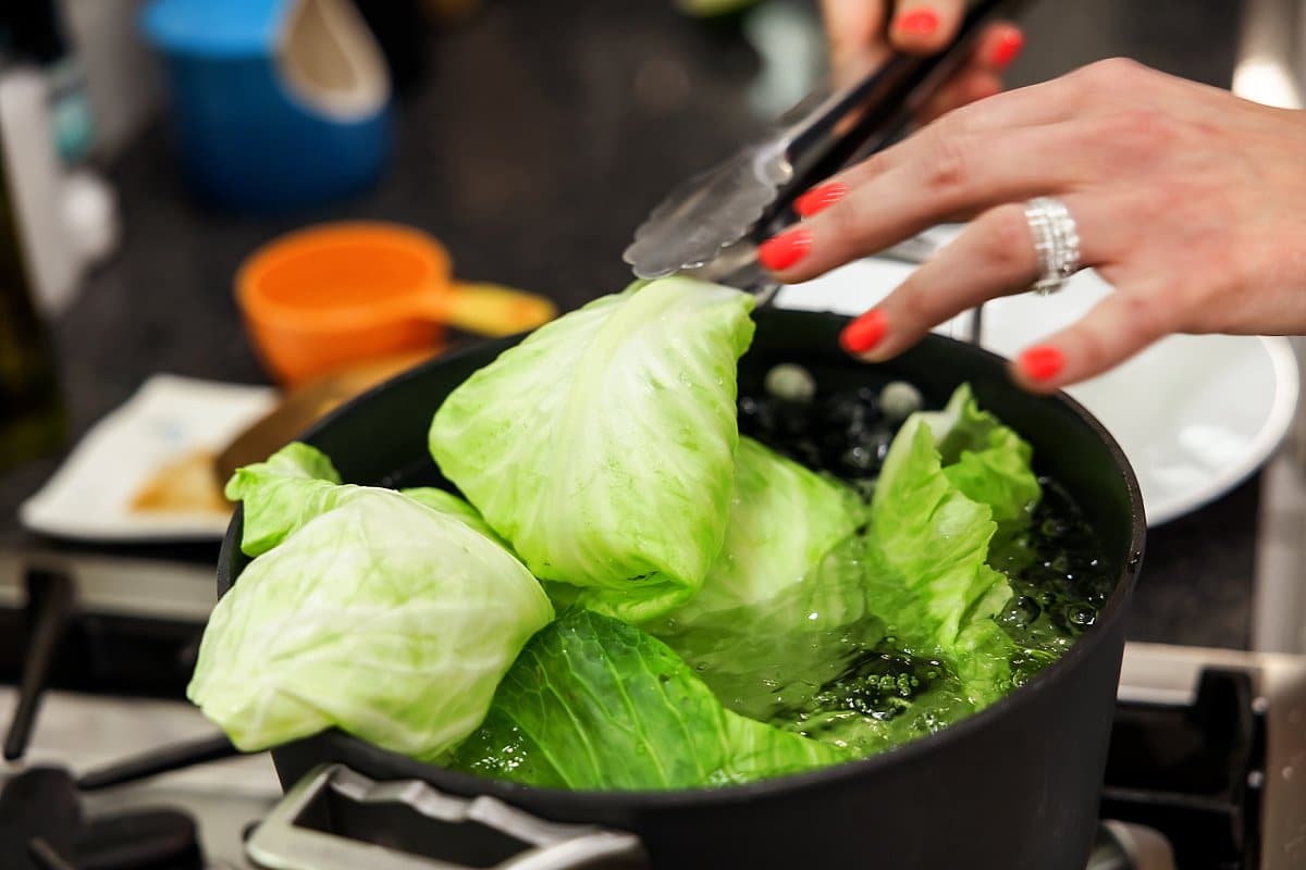 cabbage leaves being added to a pan
