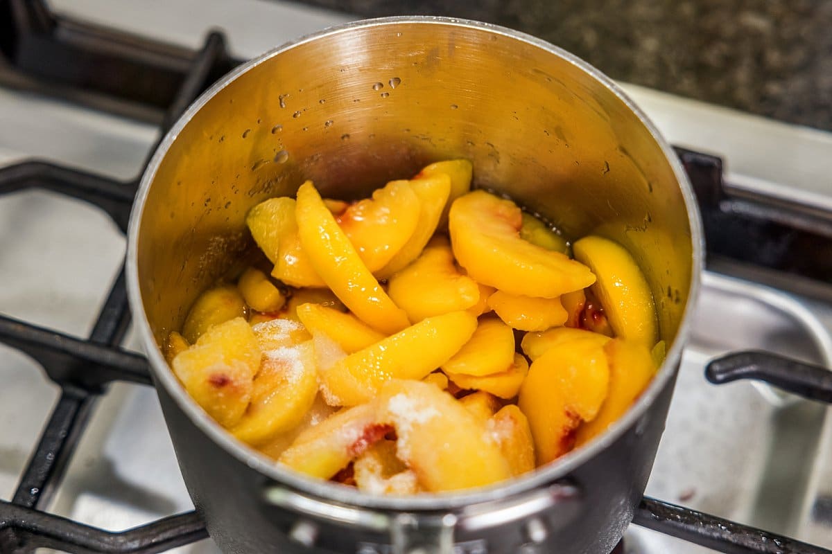 Peach slices and sugar in a sauce pan.
