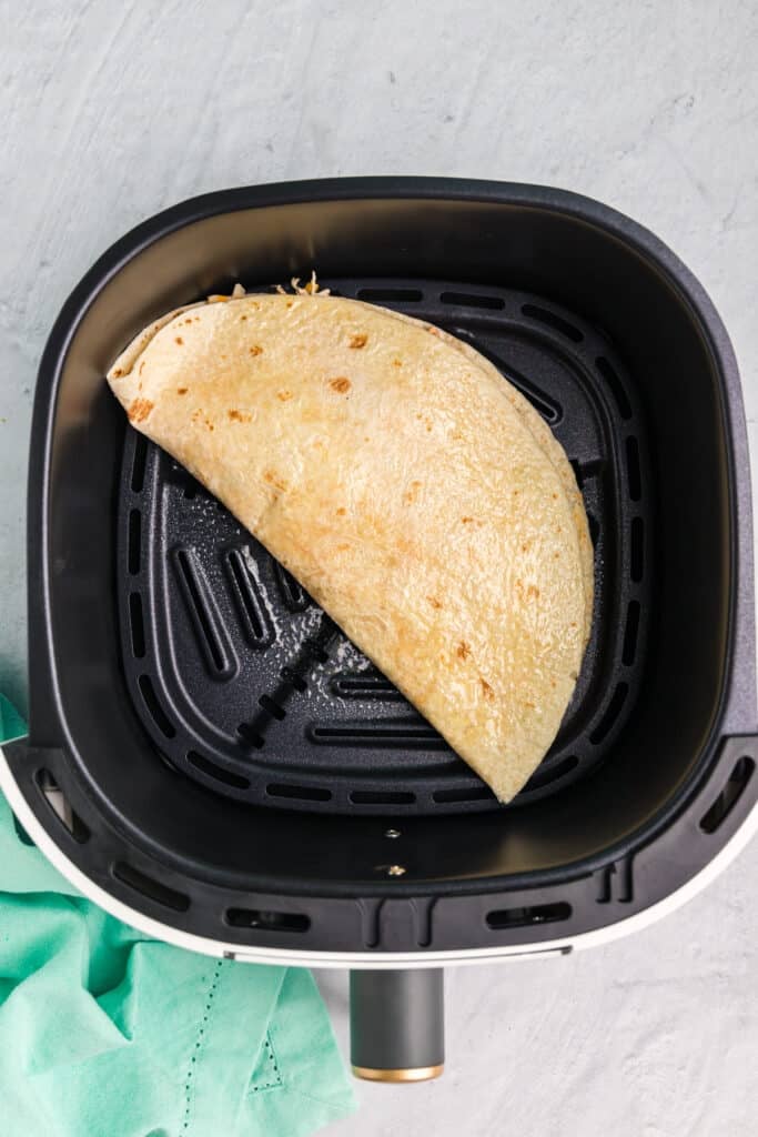 overhead shot of a quesadilla in a n air fryer basket.