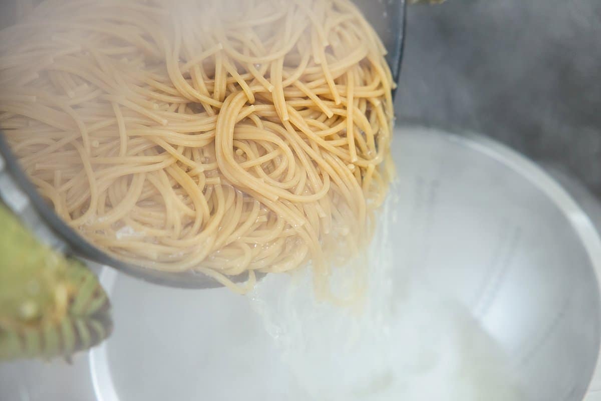 cooked pasta being added to a strainer
