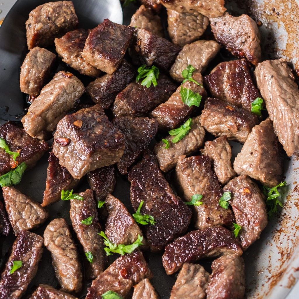 close up of garlic steak bites topped with parsley
