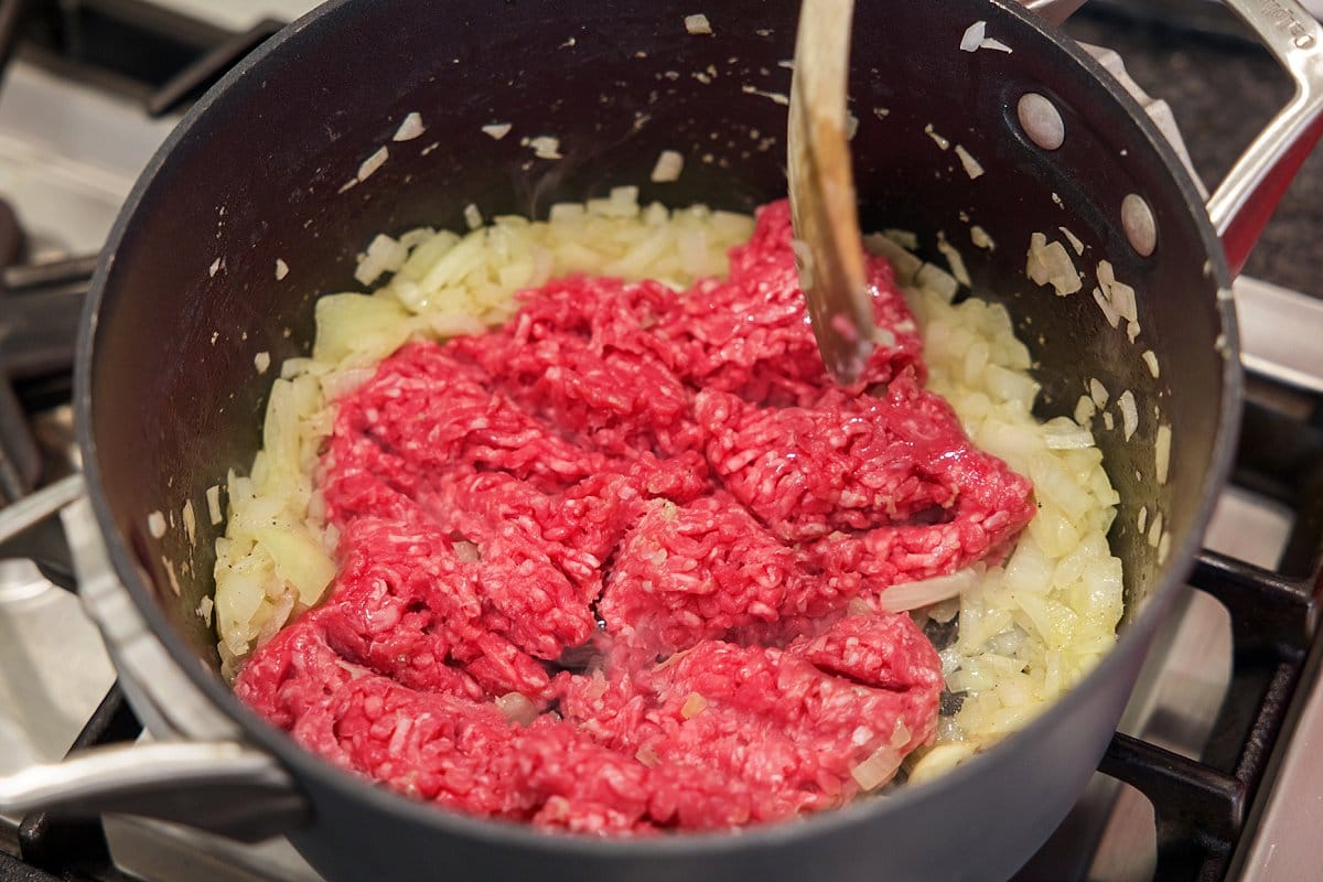 Adding ground lamb to onion in a pan