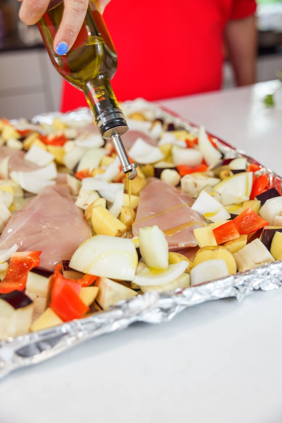 Drizzling oil over chicken and veggies