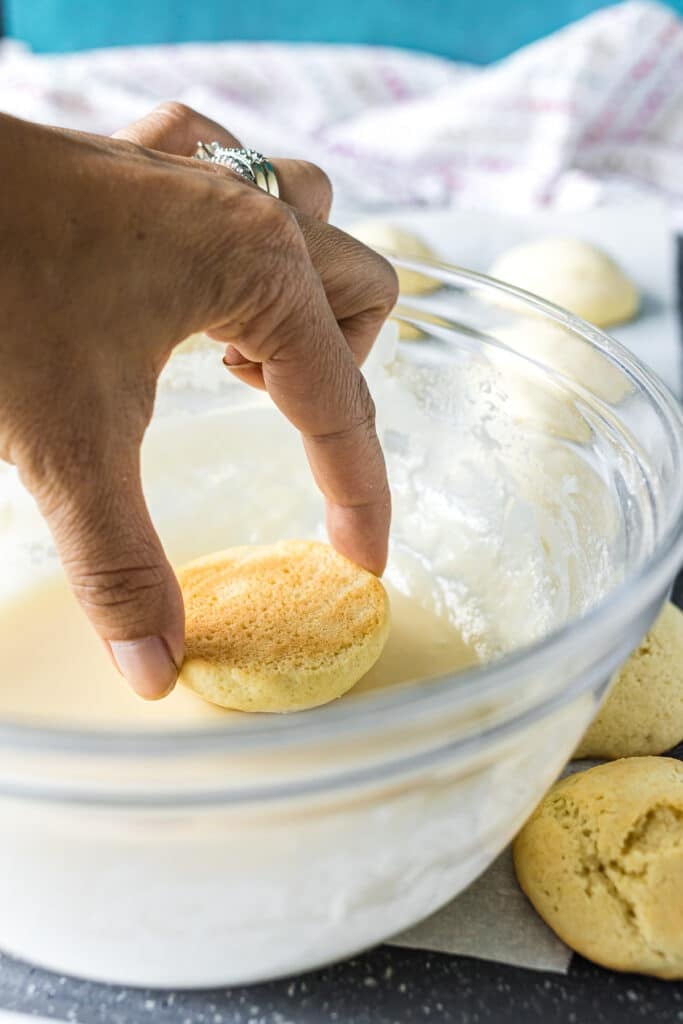 hand dipping a sugar cookie in icing.