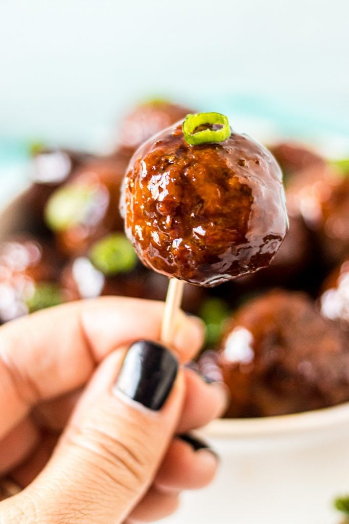 hand holding a teriyaki meatball on a toothpick