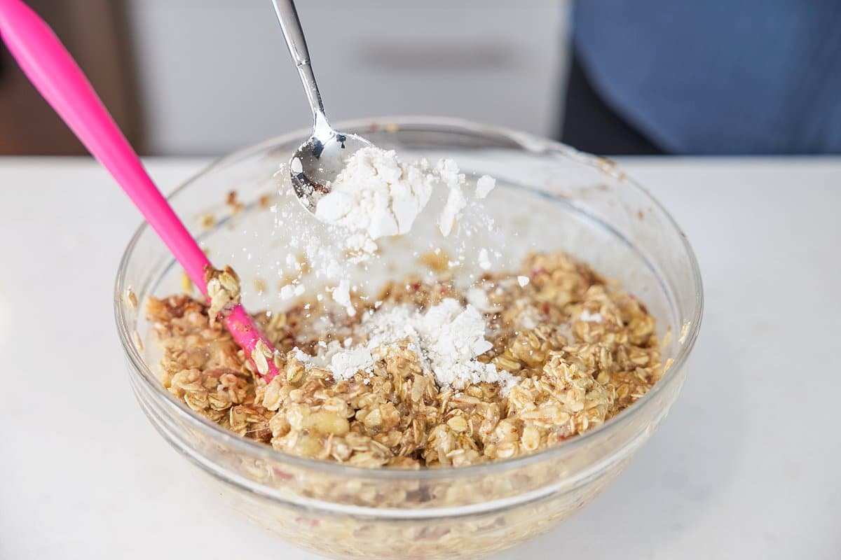 Adding protein powder to a bowl of ingredients