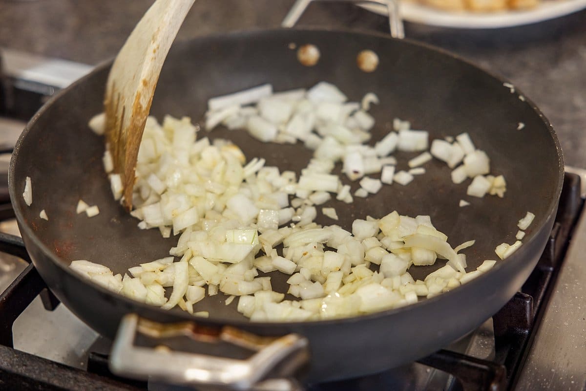 onions being cooked in a pan