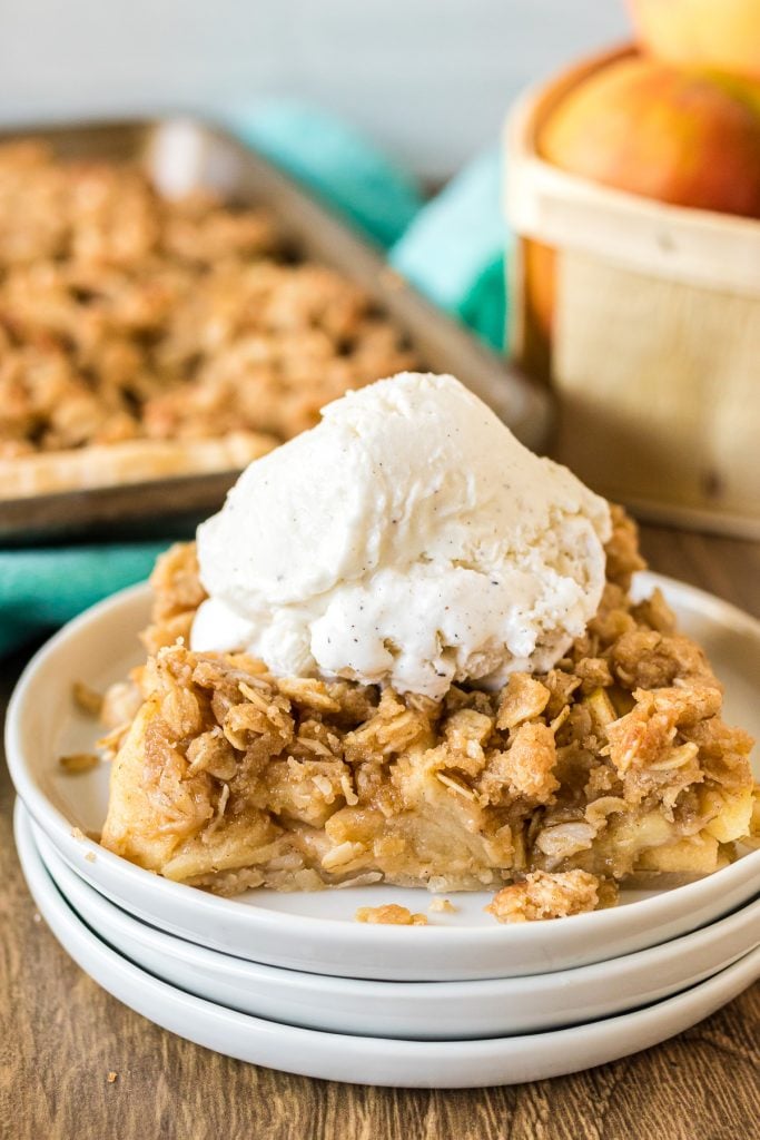 slice of apple slab pie topped with vanilla ice cream on a white plate