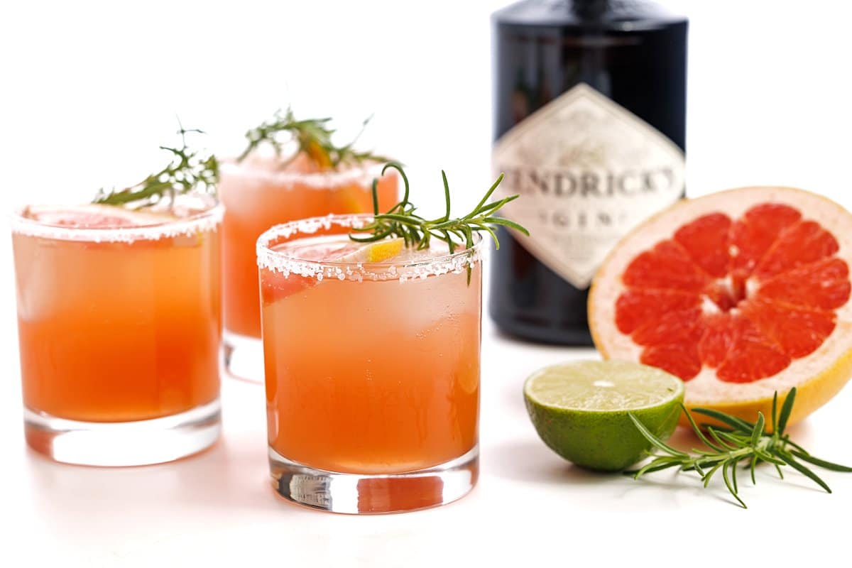 Rosemary and Gin Grapefruit Cocktails next to a fresh lime and grapefruit.