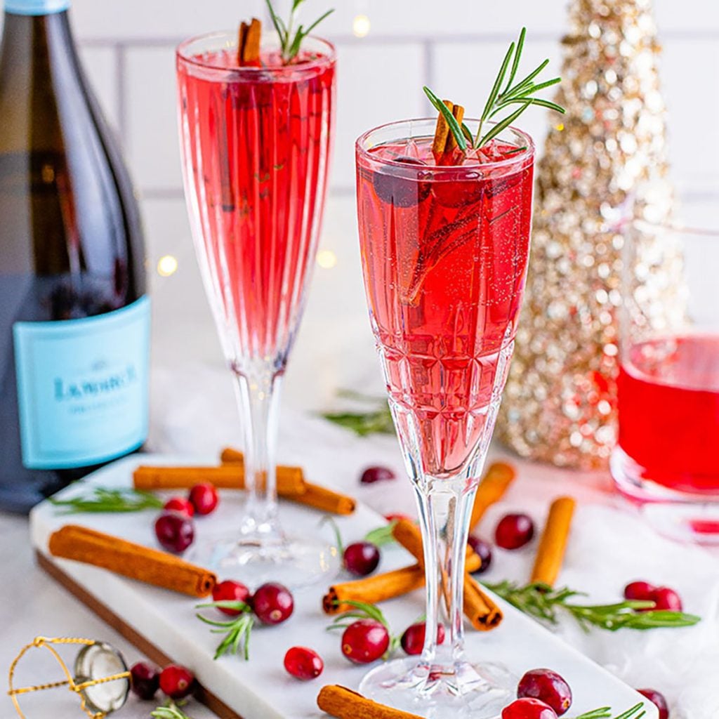 two red cocktails in champagne flutes garnished with cranberries
