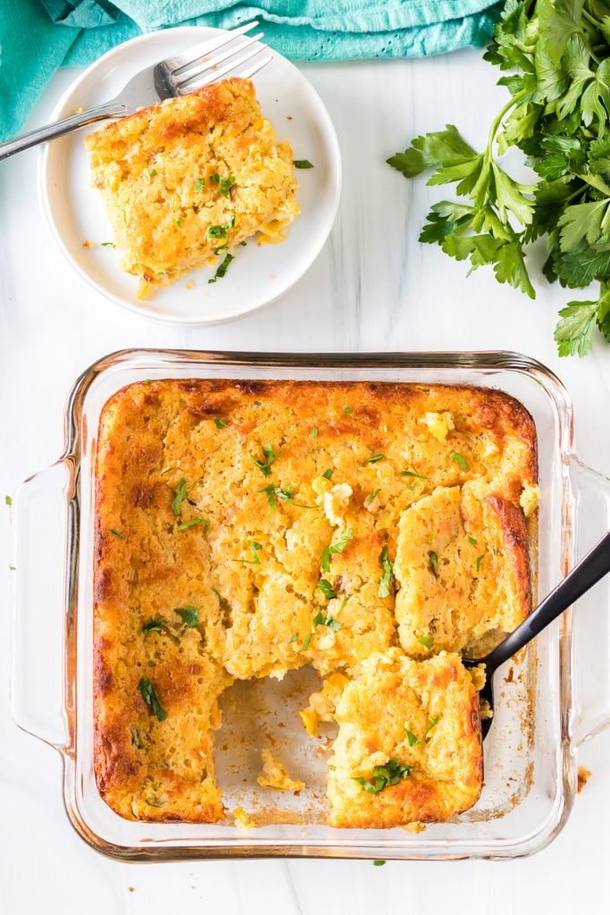 overhead shot of corn casserole with a black spoon in a baking dish