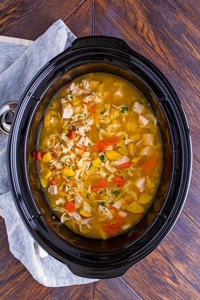 overhead shot of leftover turkey soup in the crockpot