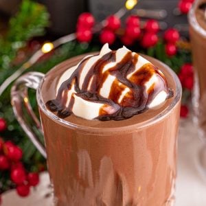 hot chocolate in a glass mug topped with whipped cream and chocolate sauce