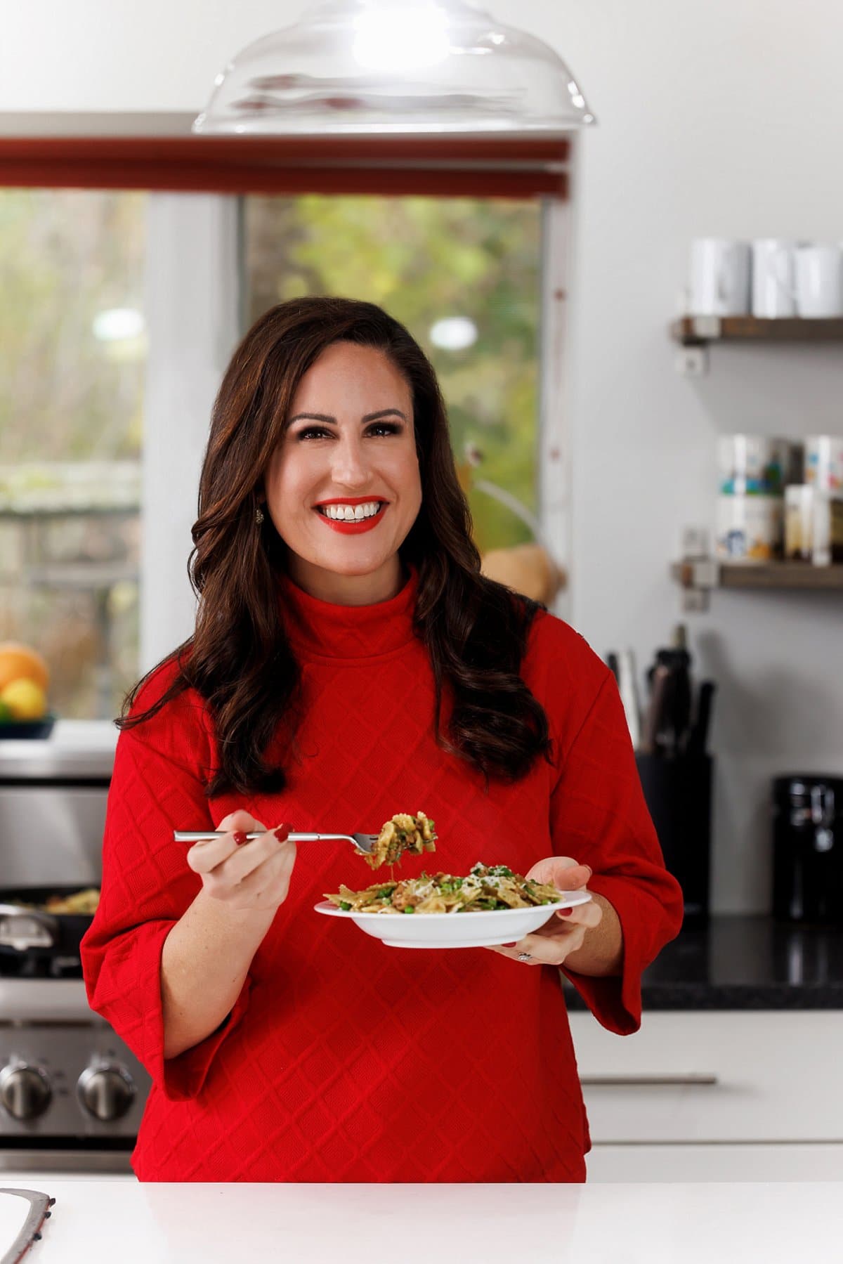 Liz eating sausage pesto pasta with caramelized onions and peas.