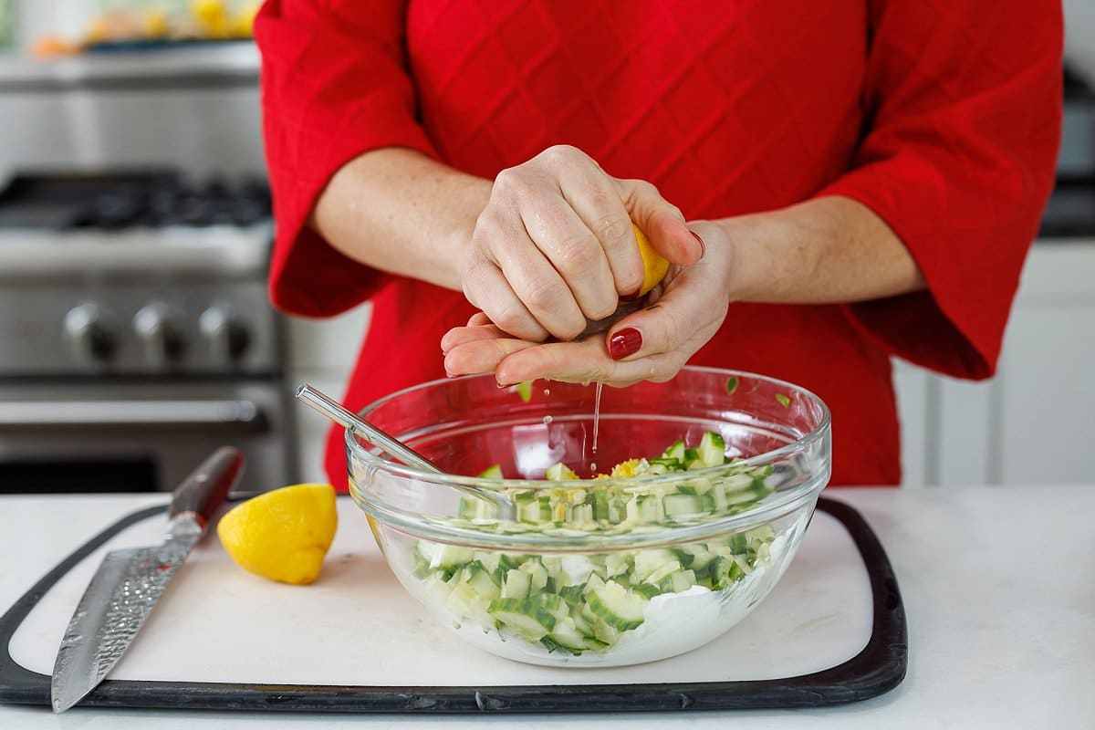 Liz juicing a lemon half with her hands.