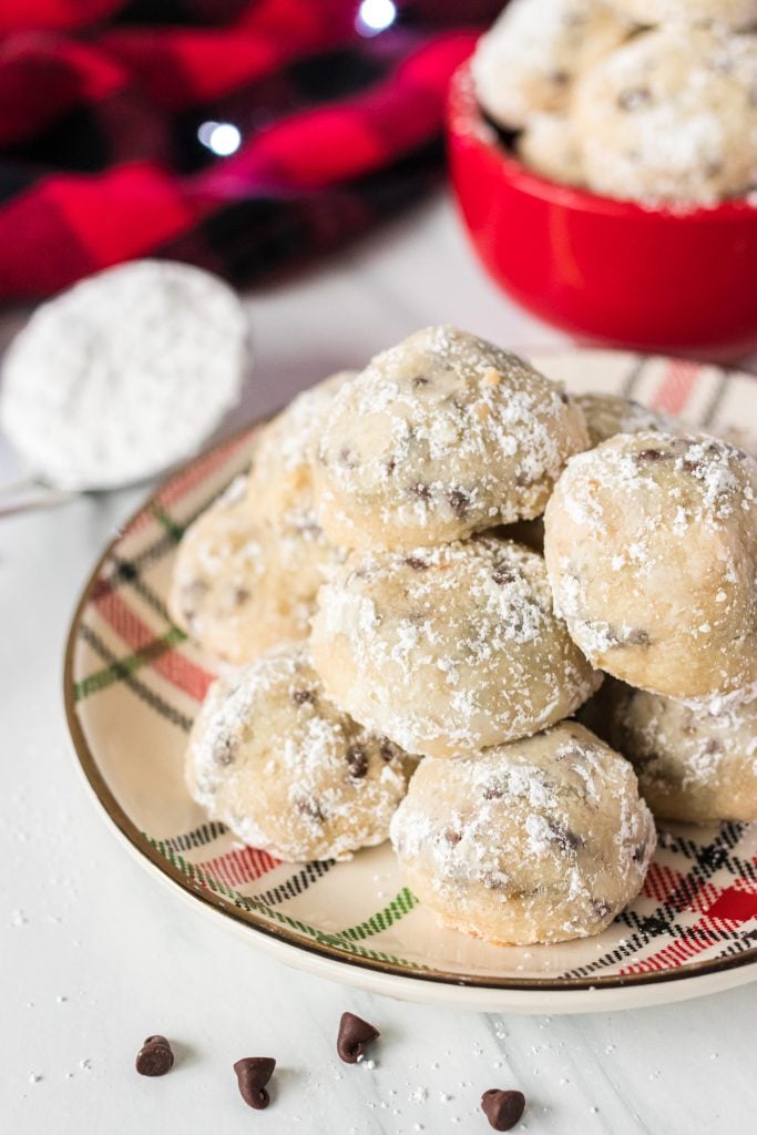 stack of snowball cookies on a plate surrounded by mini chocolate chips