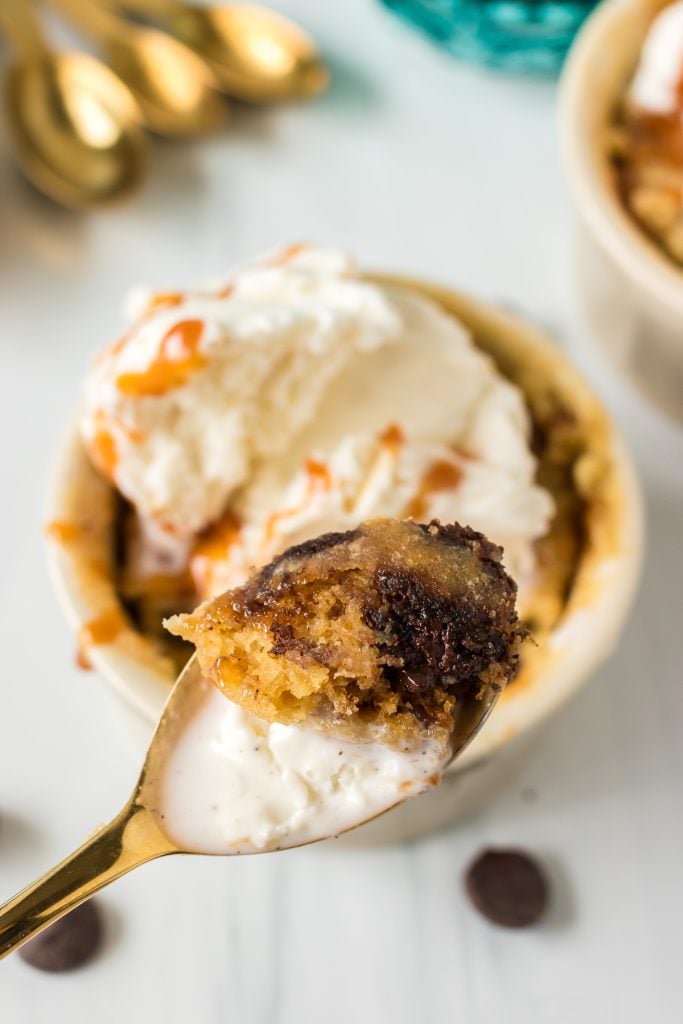 spoon scooping a bite of chocolate chip cookie and vanilla ice cream from a ramekin