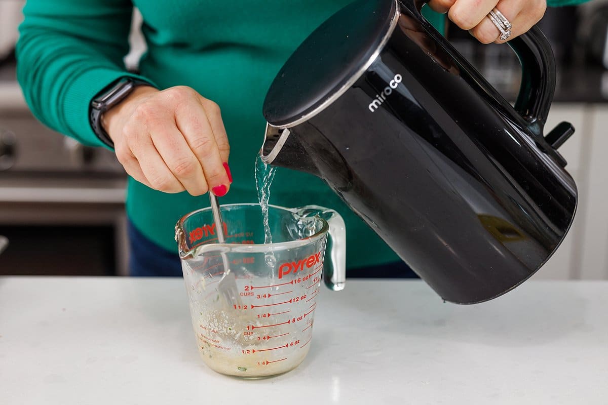 Pouring hot water into tahini sauce.
