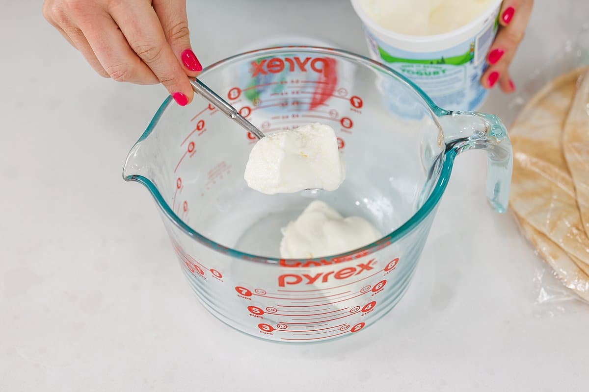 Adding yogurt to a large liquid measuring cup.