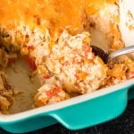 spoon scooping cheesy chicken fajita casserole from a teal baking dish