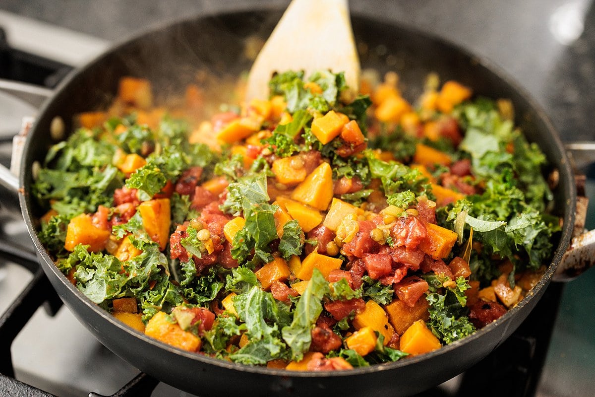 Stirring curried lentils with sweet potatoes and kale.