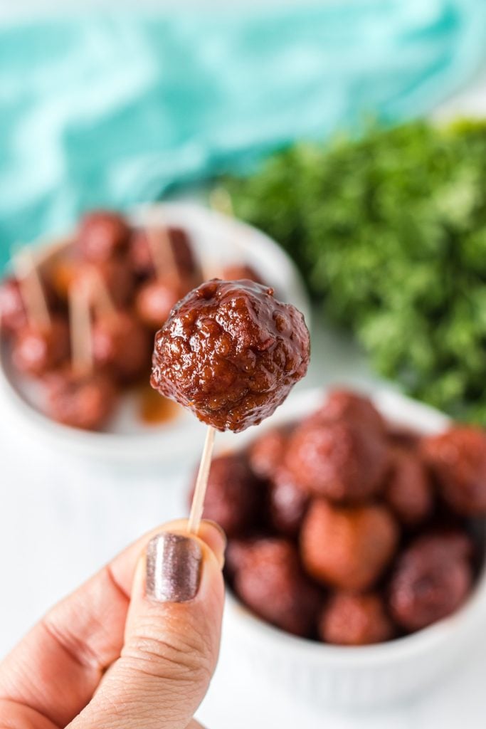 hand holding a meatball on a toothpick.