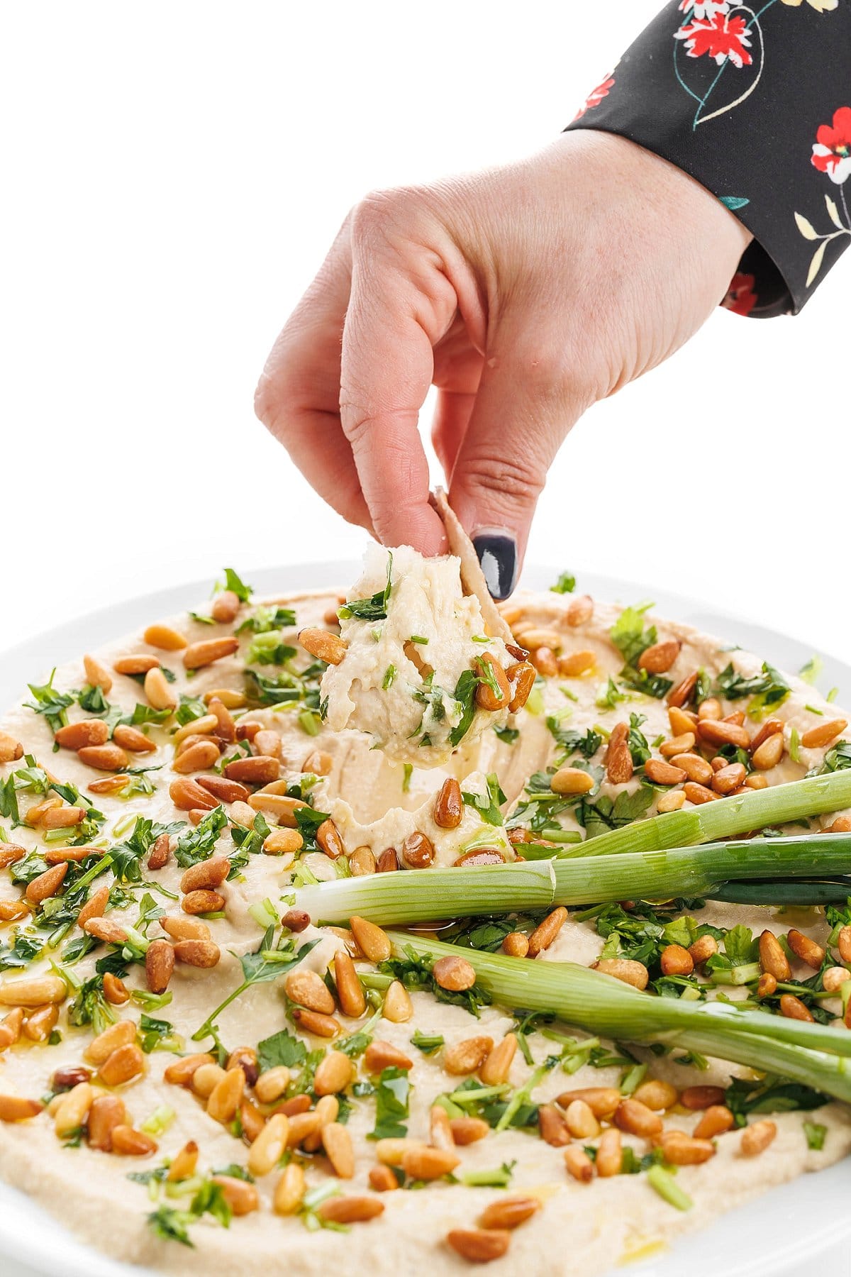 Dipping into classic hummus with toasted pine nuts.