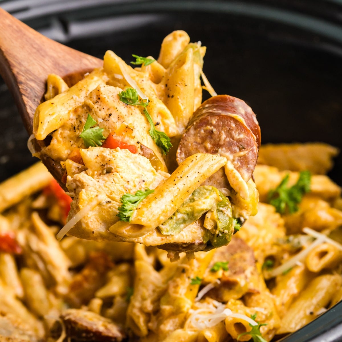 spoon scooping cajun chicken alfredo from a crockpot.