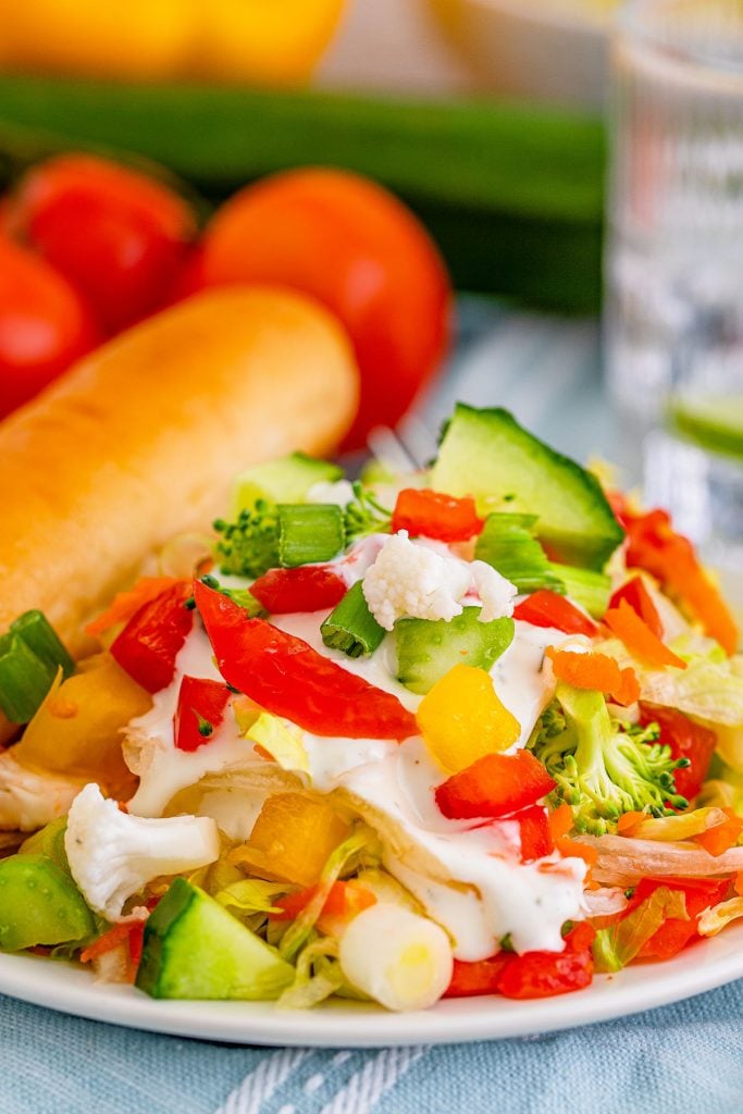 closeup of a side salad drizzled with ranch dressing.