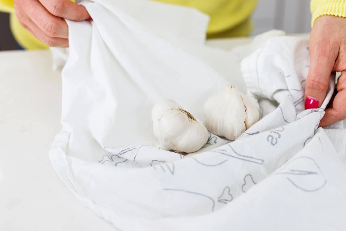 Liz using a towel to take the skin off of garlic cloves.