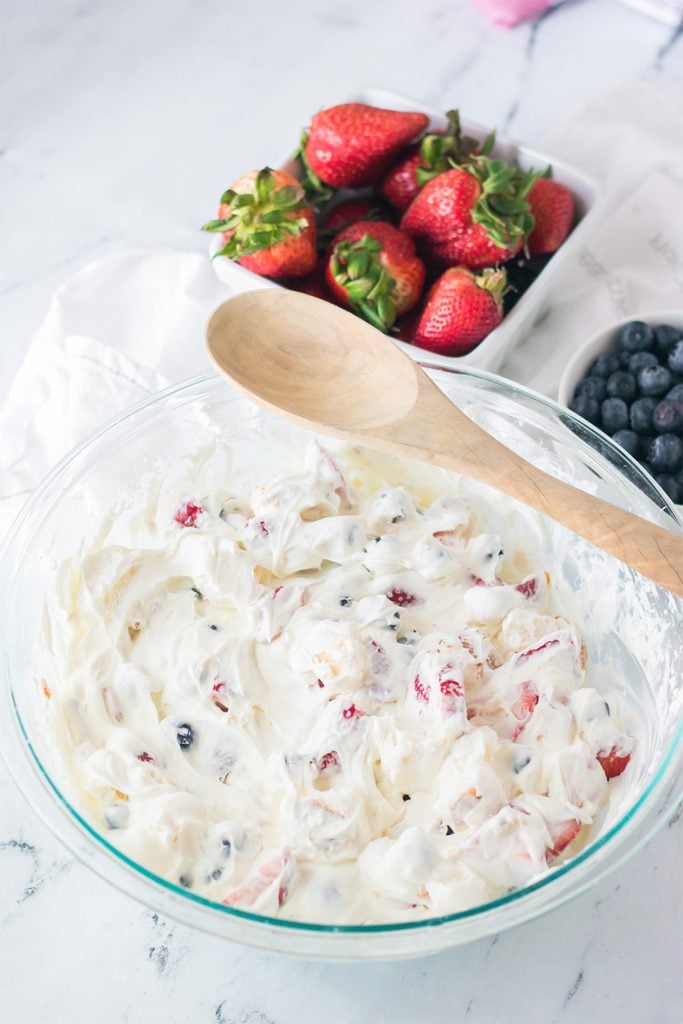overhead shot of a mixing bowl and wooden spoon filled with berry fluff salad.