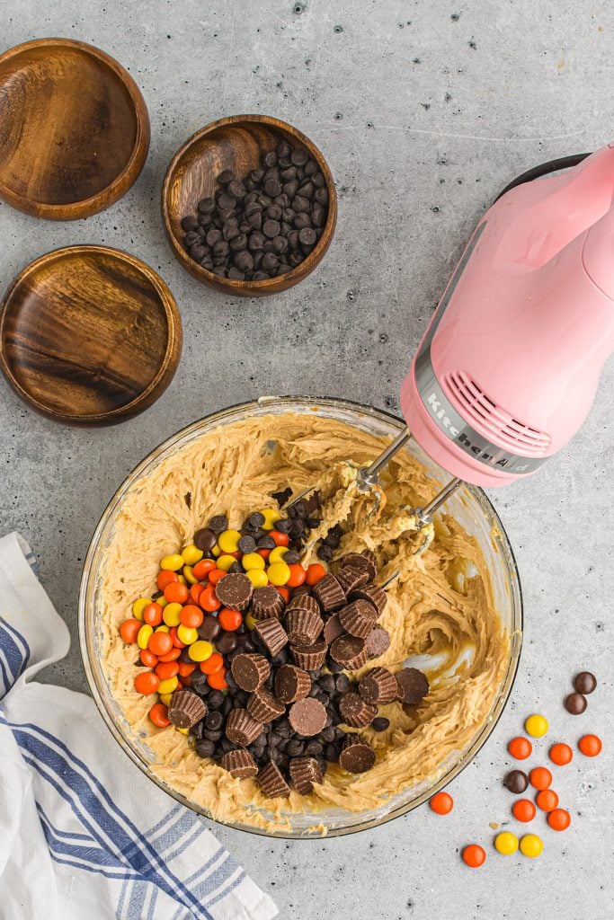 mixing bowl filled with reese's pieces, peanut butter cups.
