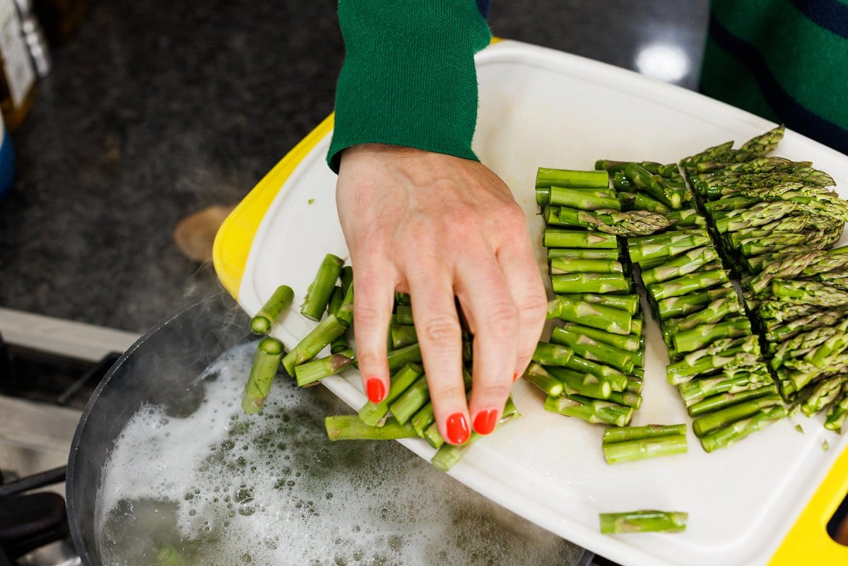 Adding cut asparagus to boiling pot.