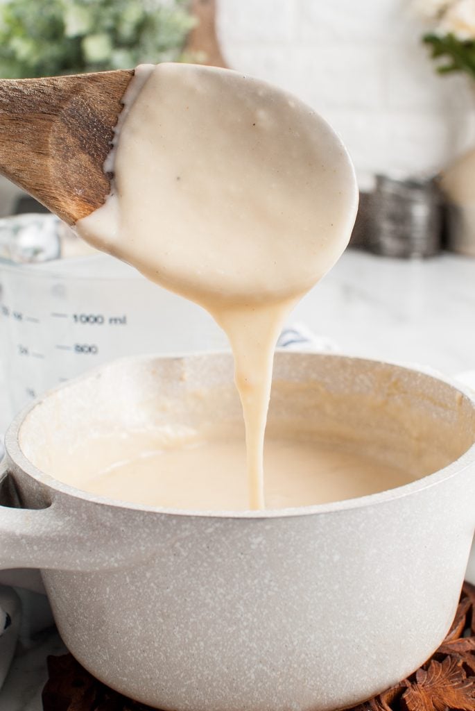 wooden spoon dipping into a saucepan of cream of chicken soup.