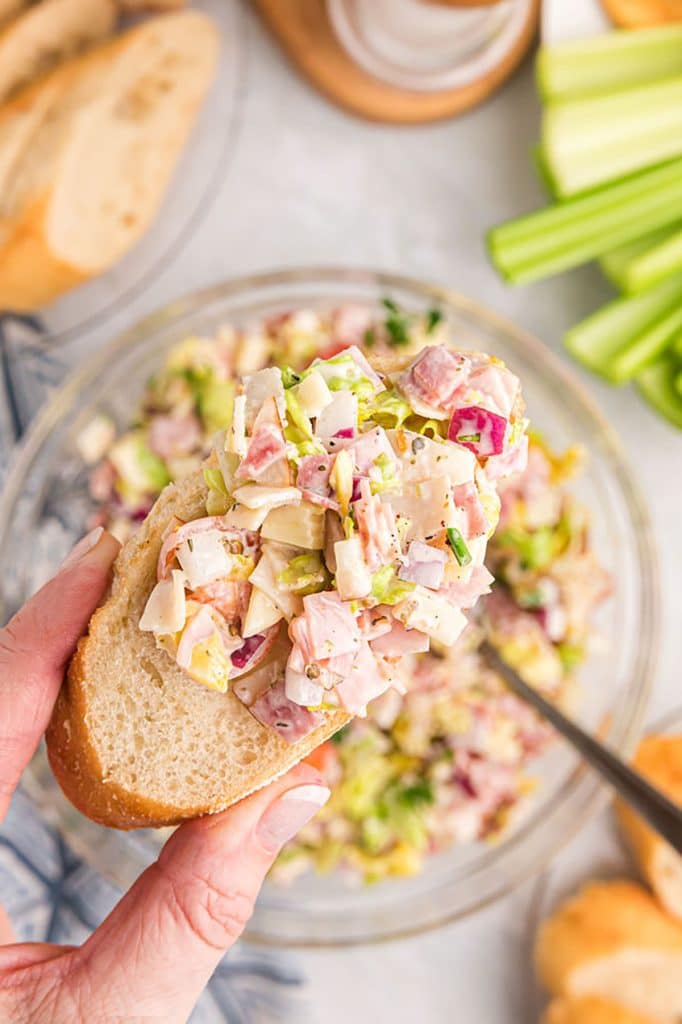 hand holding a piece of bread with hoagie dip on it.