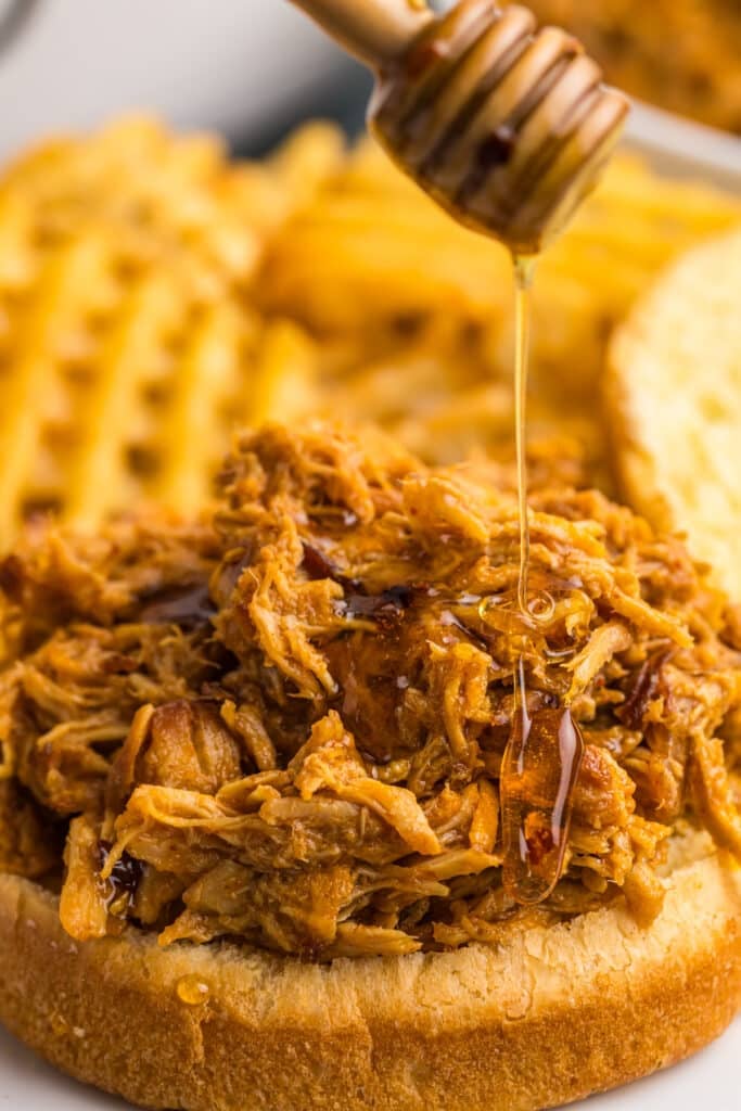 honey drizzling on a shredded chicken sandwich.