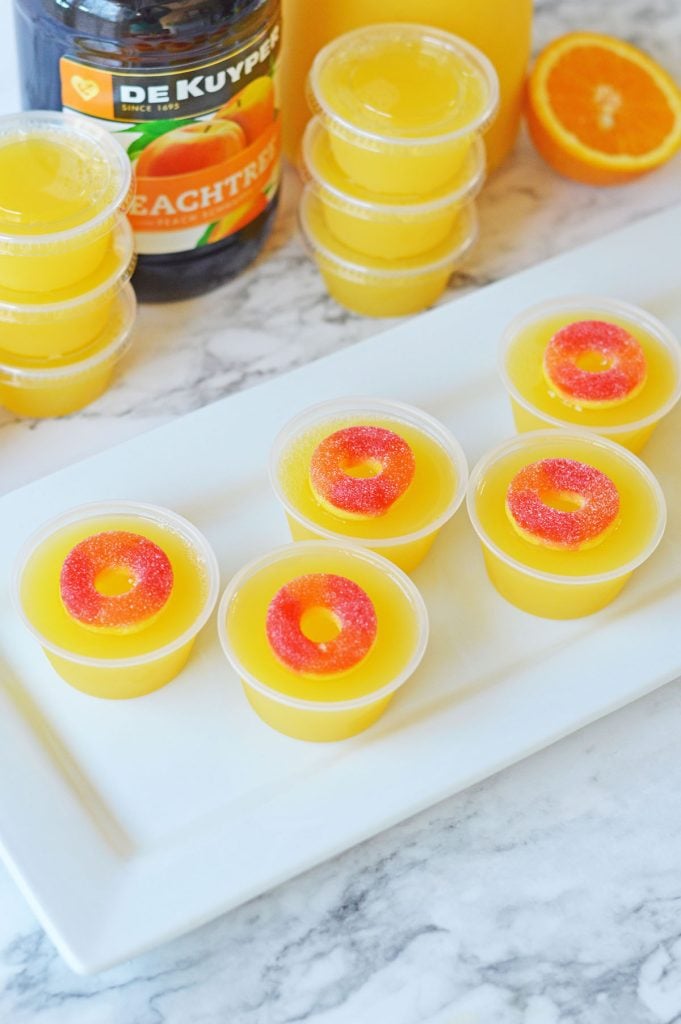 overhead shot of peach jello shots on a white plate.
